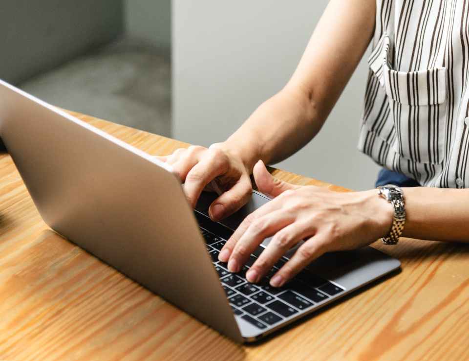 person using macbook pro on brown wooden table